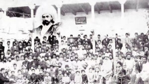 لقطة تاريخية من الفيلم الوثائقي البهائي مائتا عام من التاريخ الخفي تظهر تجمعاً قديماً مع صورة رمزية في الخلفية.