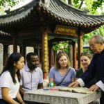 شيخ صيني يشرح تعاليم الديانة الكونفوشيوسية من كتاب قديم لمجموعة من السياح في معبد تاريخي يحمل شعار ABN NEWS