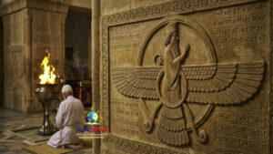 نقش حجري لرمز الفراوفهر الزرادشتي على جدار معبد مع شخص يصلي وشعلة النار المقدسة في الخلفية.