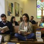 A diverse group of individuals sitting together in an interfaith sanctuary, studying different religious texts and representing the exploration of multiple spiritual paths.